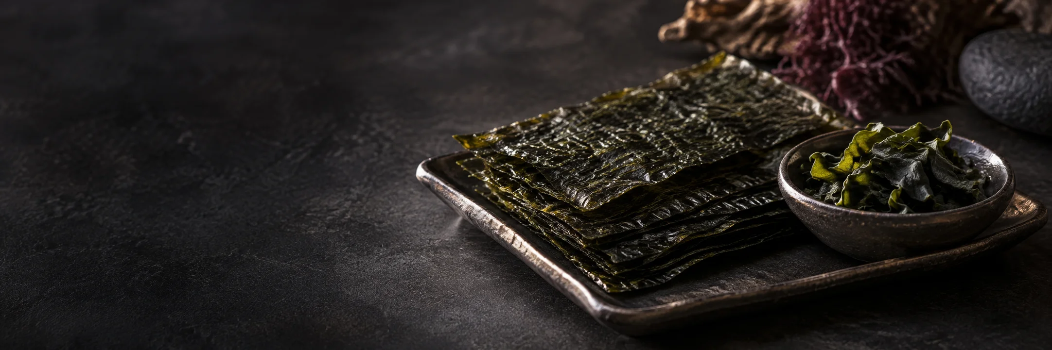 Folded dark-green dried seaweed sheets and curled seaweed pieces illustrating almela2002 algae food arsenic metals research context.