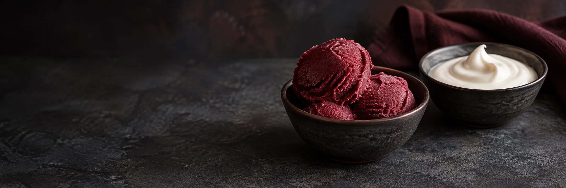 Separate dishes of red fruit sorbet scoops and thick white sour cream illustrating sorbet ingredient context.