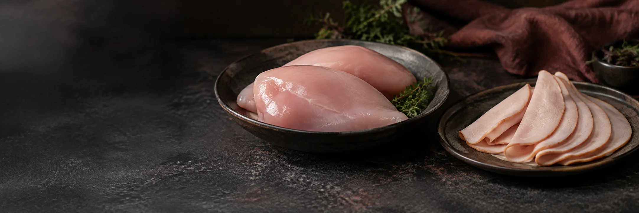 Separate dishes of raw turkey breast portions and thin cooked turkey slices illustrating turkey luncheon meat ingredient context.
